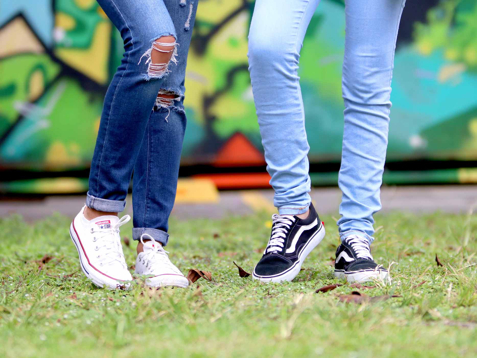 Zwei Frauen tragen Skinny Jeans vor einer Graffitiwand