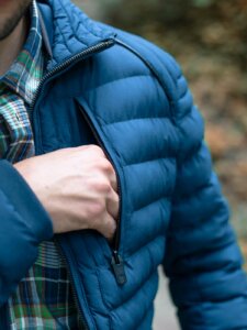 Detailaufnahme, wie ein Mann in die Brusttasche seiner Jacke greift.