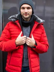 Junger Mann präsentiert eine rote Winterjacke