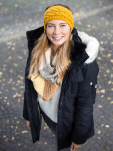 Junge Frau mit schwarzer Winterjacke und gelbem Stirnband