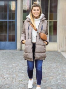 Junge Frau mit Winterjacke, Umhängetasche und Half Bun