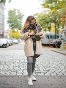 Junge Frau steht auf einer Straße und schaut zu ihrer Umhängetasche. die sie gerade öffnet