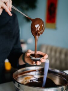 Geschmolzene Schokolade wird von einer Kelle in ein Schälchen gefüllt.