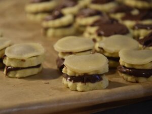 Kekse auf einem Backpapier mit Nutella und Marzipan geschichtet.