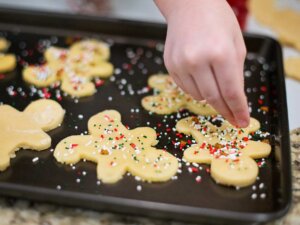 Bunte Streusel werden auf Ausstechplätzchen gestreut.