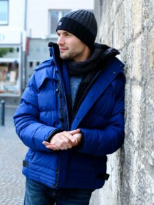 Junger Mann in blauer Winterjacke und mit Mütze