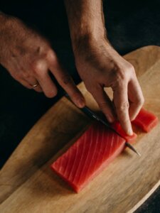 Fisch wird auf einem Holzbrett geschnitten