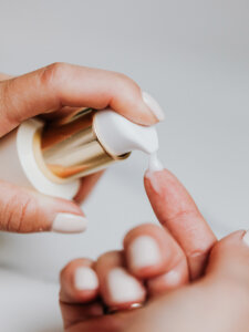 Creme wird aus einem Spender auf den Finger gegeben