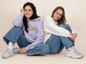 Zwei Teenager im beigen und lila Hoodie sitzen auf dem Boden