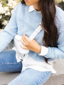 Detailaufnahme von junger Frau im pastellblauen Pulli und weißer Bauchtasche