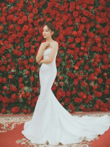 Braut im Fishtail Kleid vor einer Rosenwand