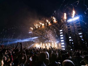 Viele Menschen stehen nachts vor einer Festivalbühne und feiern