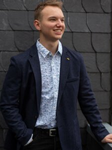 Junger Mann in Sakko, Hemd und Hose mit Gürtel