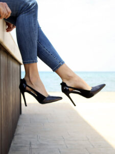 Weibliche Beine in 7/8-Jeans mit schwarzen High Heels