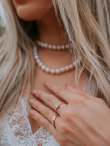 Gesichtslose Frau mit Perlenkette und Ringen