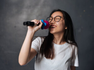 Frau mit Brille singt voller Freude in ein Mikrofon
