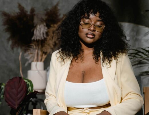 Sitzende Plus Size Frau mit pastellgelbem Oversize Blazer und weiter, pastellgelber Hose
