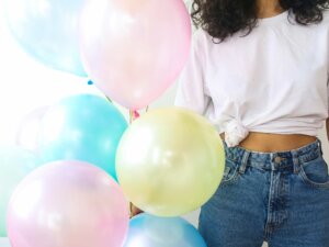 Luftballons in Candy Colors, gehalten von einer modisch gekleideten jungen Frau