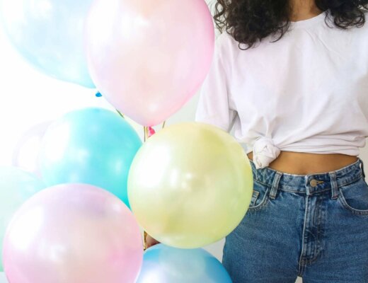 Luftballons in Candy Colors, gehalten von einer modisch gekleideten jungen Frau