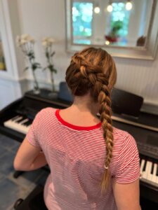 Frau am Keyboard von hinten mit seitlich geflochtenem Zopf