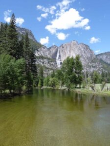 Wasserfall im Yosemite Nationalpark, der einen Berg herunterfällt, davor Bäume und ein See