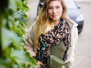 Junge Frau mit olivfarbenem Oberteil und Schal mit Leoprint
