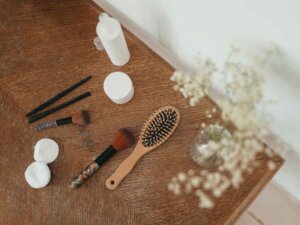 Make-up und Kosmetikartikel aufgereiht auf einer braunen Unterlage