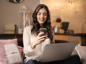 Eine Frau sitzt an ihrem Laptop und Handy