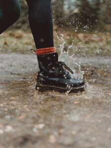 Schwarzer Damenstiefel tritt in eine Pfütze