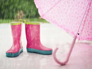 Pinke Gummistiefel und rosa Regenschirm stehen im Regen