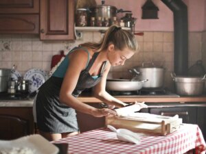 Junge Frau in der Küche rollt Teig aus