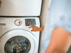 Ein Mann wählt an der Waschmaschine das Waschprogramm aus.