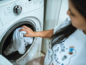 Frau steckt Kleidung in die Waschmaschine