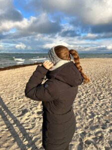 Ein Mädchen steht am Strand und trägt ein Stirnband