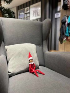 Rot gekleideter Elf sitzt in einem Bekleidungsgeschäft auf einem Sessel