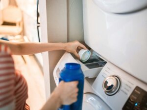 Frau gießt Flüssigwaschmittel in die Waschmaschine.