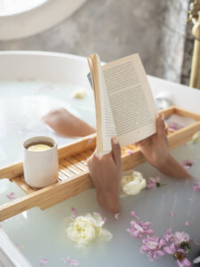 Hände einer Frau, die in der Badewanne liegt und liest