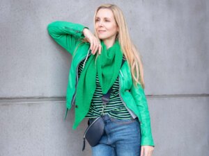 Eine Frau, die eine grüne Jacke und ein gestreiftes Shirt trägt