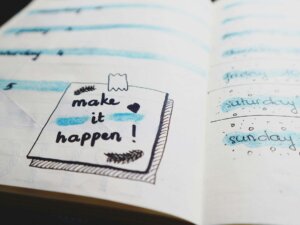 Ein aufgeschlagener Planer zeigt eine Seite mit dem Spruch "make it happen".