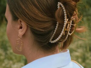 Eine Frau hat ihre Haare durch eine goldene Perlenhaarklammer hochgesteckt