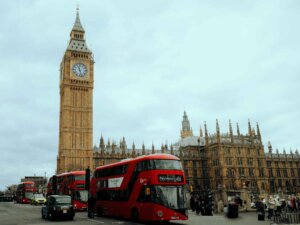 Der Big Ben in London mit einem roten Doppeldeckerbus davor.