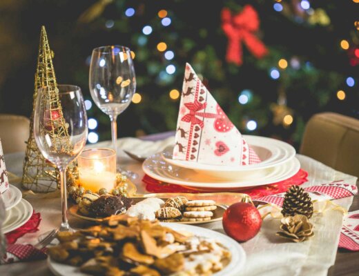 Ein Tisch, der weihnachtlich dekoriert ist und auf dem ein Teller mit Serviette und ein Glas stehen