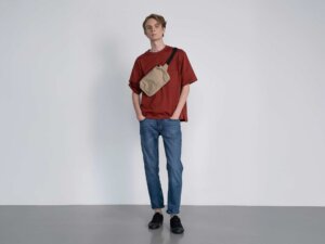 Ein großer schlanker Mann in Jeans und T-Shirt posiert vor einem weißen Hintergrund. 