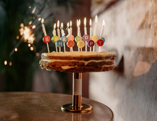 Ein Naked Cake mit Happy-Birthday-Kerzen steht auf einem Tisch.