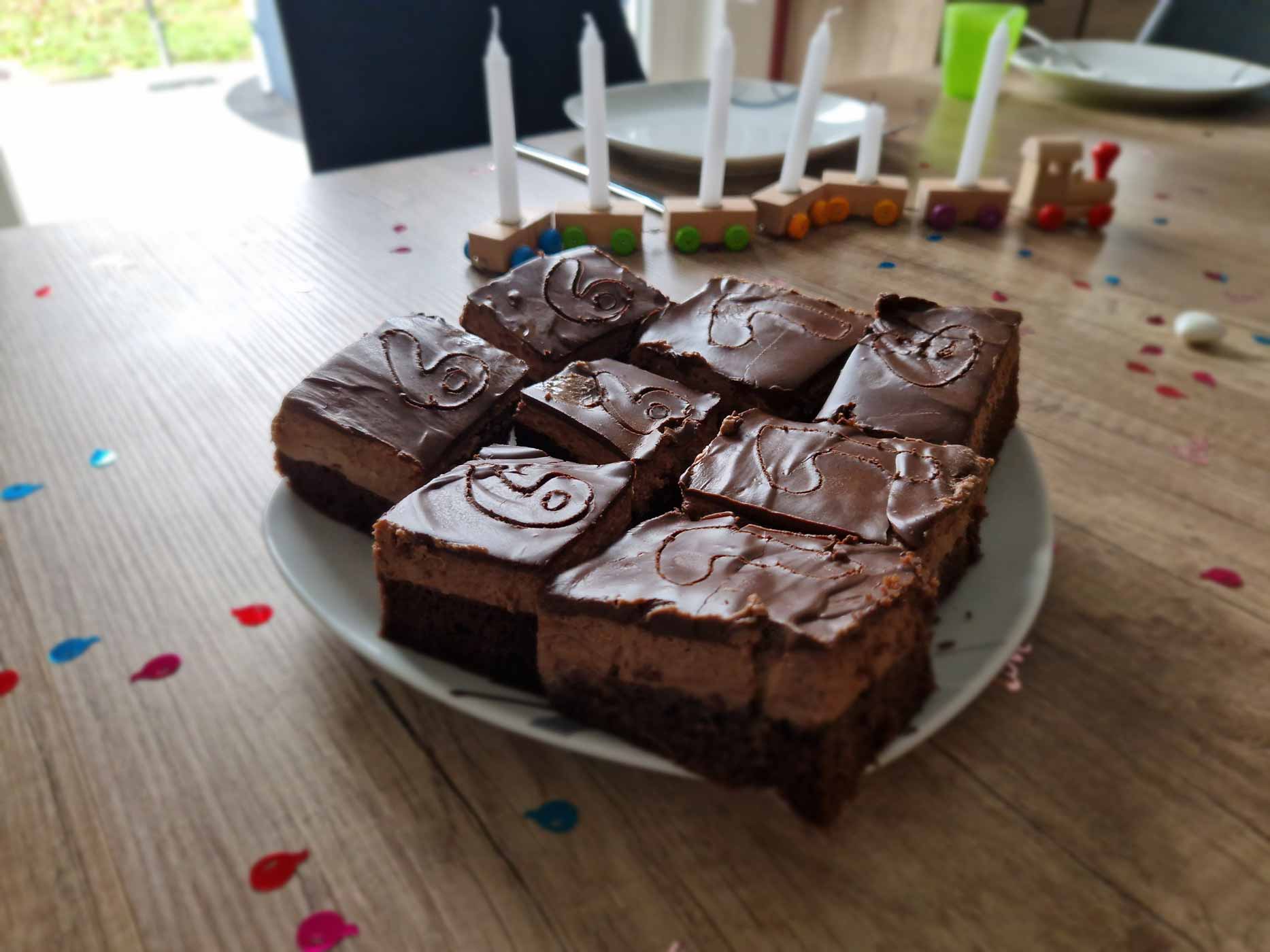 Geburtstagskuchen Schokolade Nutellaschnitten liegen auf einem Teller, der auf einem kindlich-dekorierten Geburtstagstisch steht.