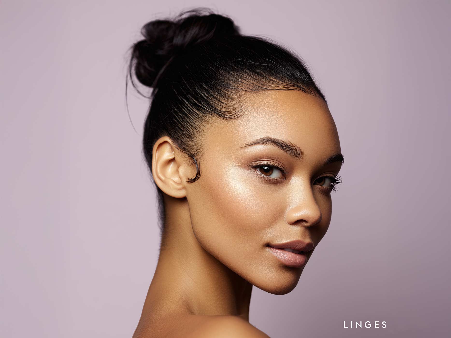 Eine Frau guckt in die Kamera, sie trägt ihre Haare zurückgegelt und in einem Dutt.