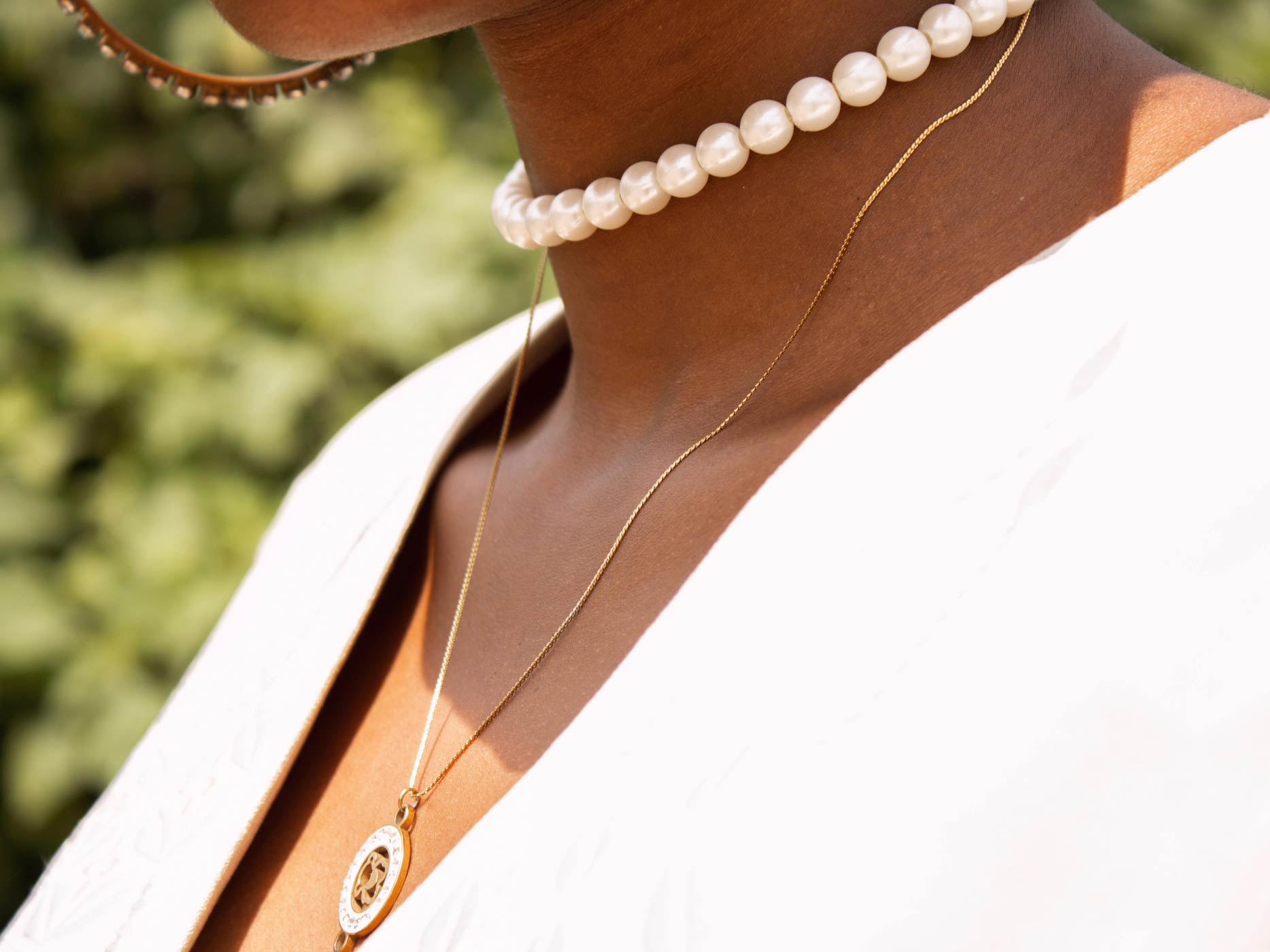 Frau trägt eine Perlenkette und eine längere, goldene Kette um den Hals