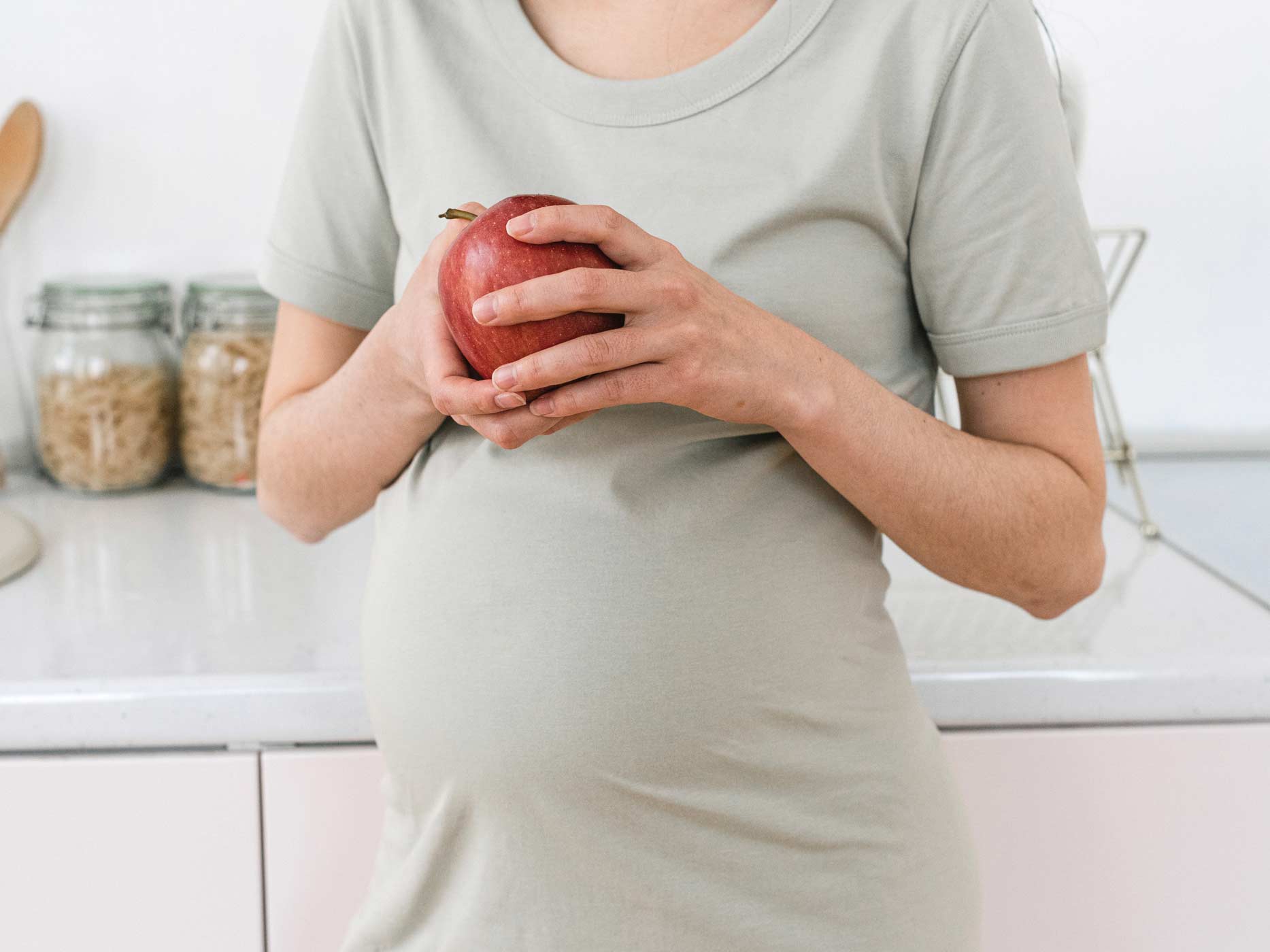 Schwangere mit einem Apfel vor dem Bauch