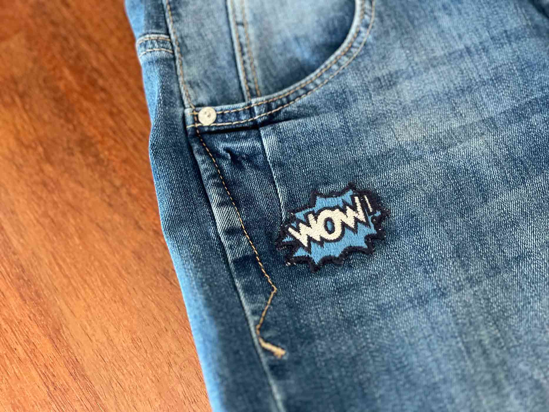 Jeans mit Patch, die auf einem Holzfußboden liegt