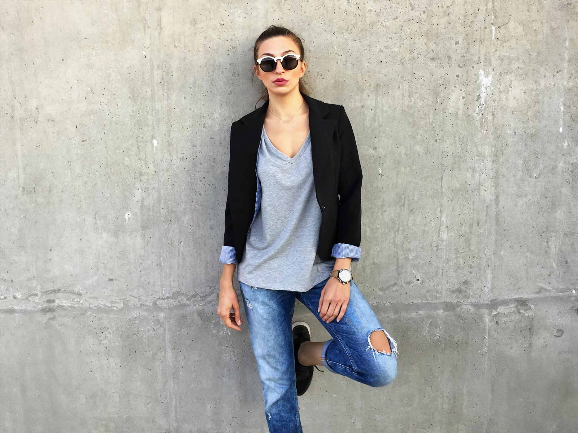 Frau trägt Jeans, ein graues Shirt und einen schwarzen Blazer